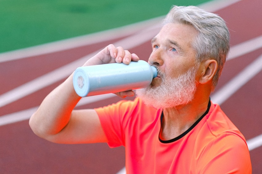 Foto van man die flesje met water drinkt tijdens het sporten